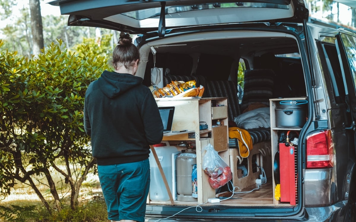 Person inspiziert das eigene Gefährt für den Wohnmobil-Urlaub