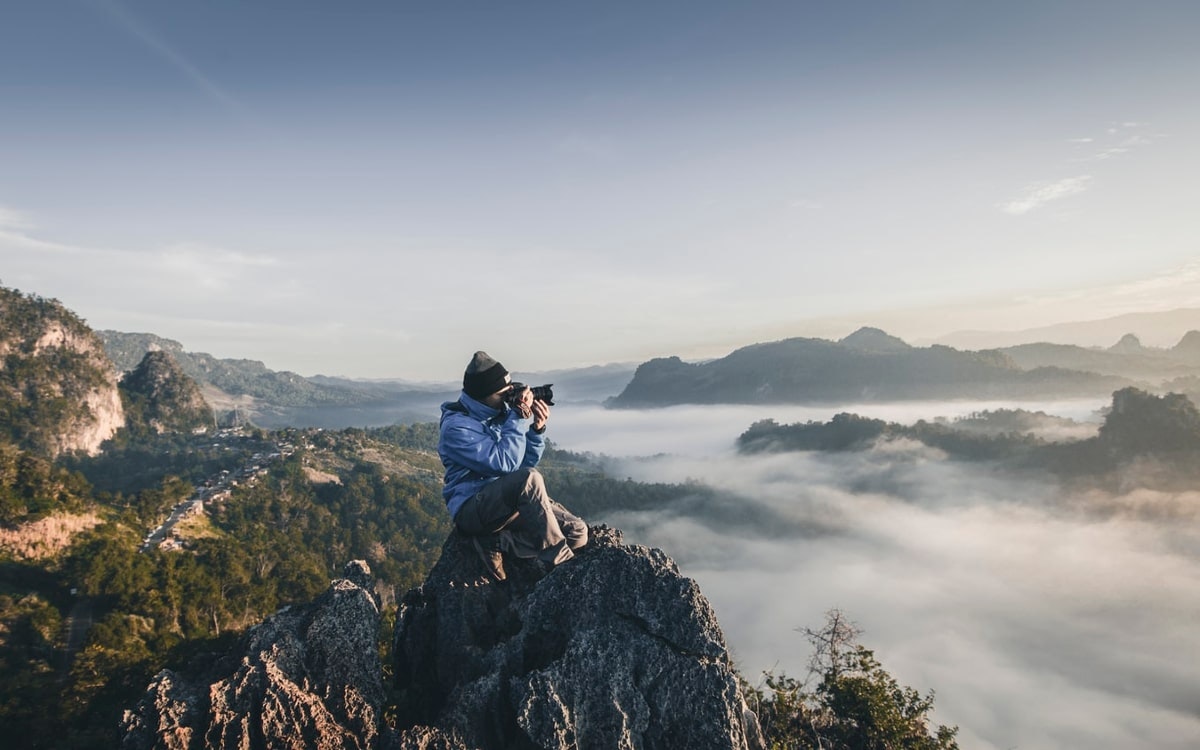 Richtig Fotografieren: Person sitzt auch einem Felsen und fotogrfiert