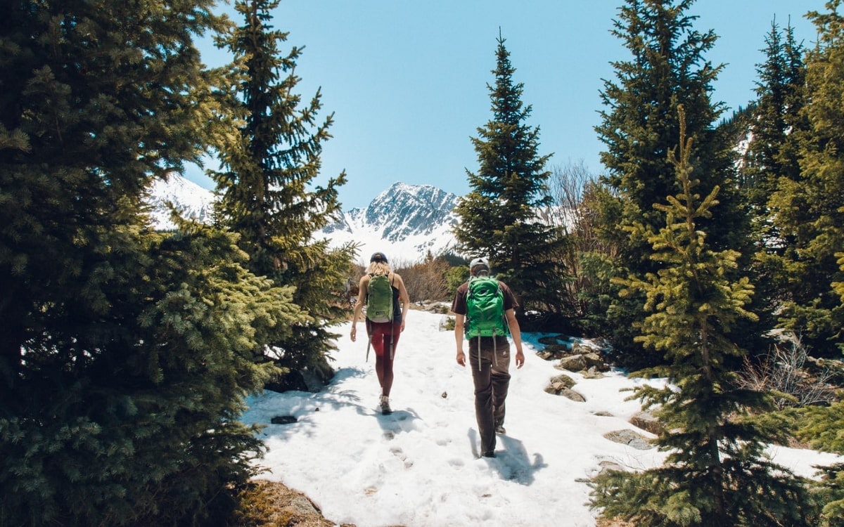 Bei der Wanderung planen auch die Strecke berücksichtigen. Wie hier die zwei Personen, die durch ein Schneefeld wandern