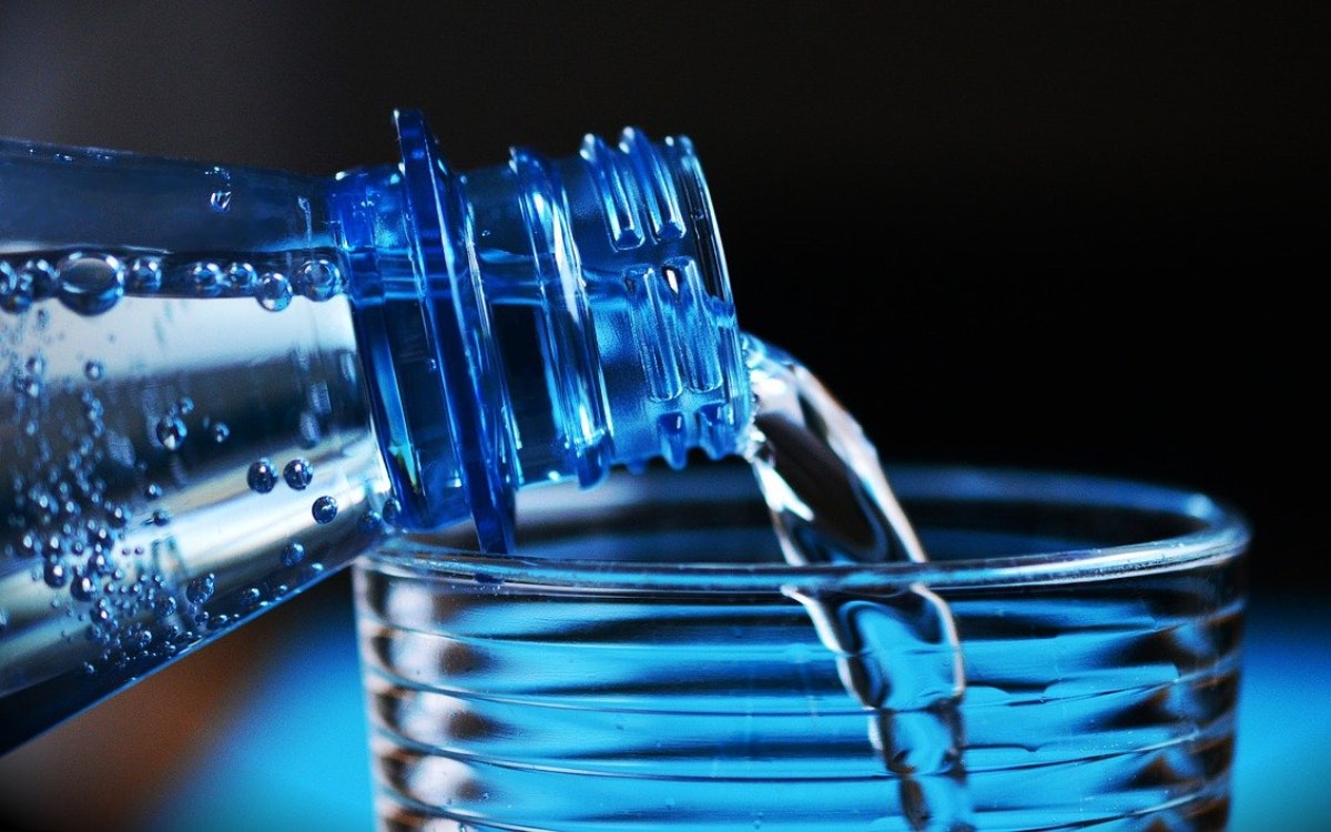 Wasser wird aus einer Flasche ins Glas gegossen