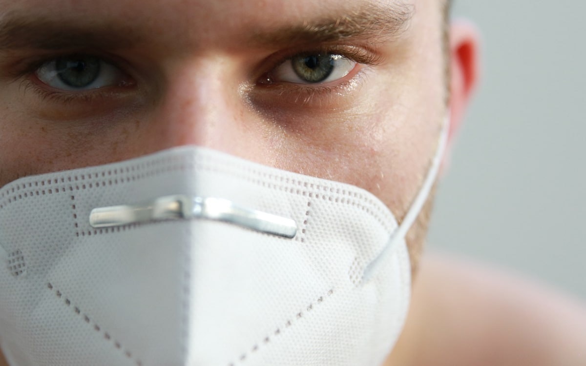 Mann mit FFP2-Maske schaut ernst in die Kamera