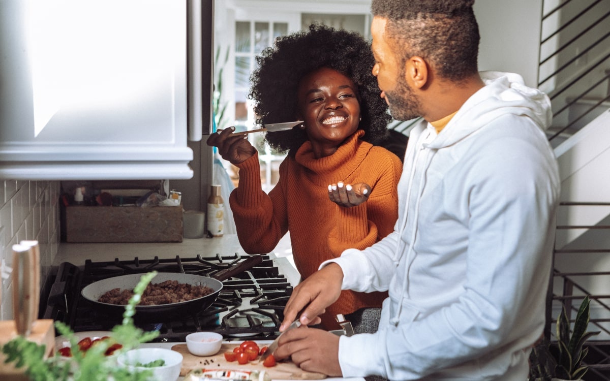 Ein Pärchen kocht zusammen und schmeckt das Essen ab