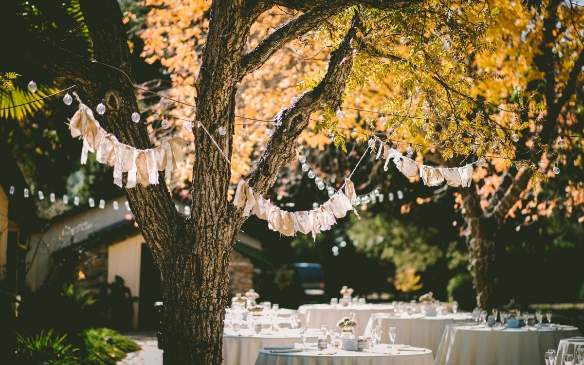 Garten mit Laternen und weißen Stofffetzen dekoriert für eine Boho Style Hochzeit