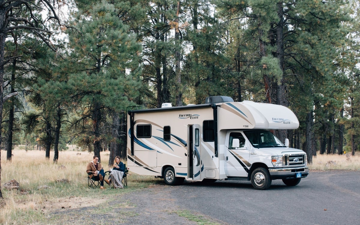 Pärchen parkt mit Wohnmobil auf Parkplatz am Wald